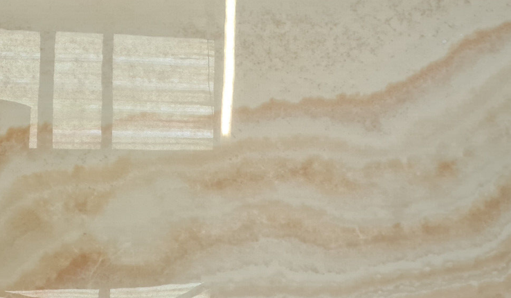 Polished marble slab with beige and brown veining on a reflective surface.